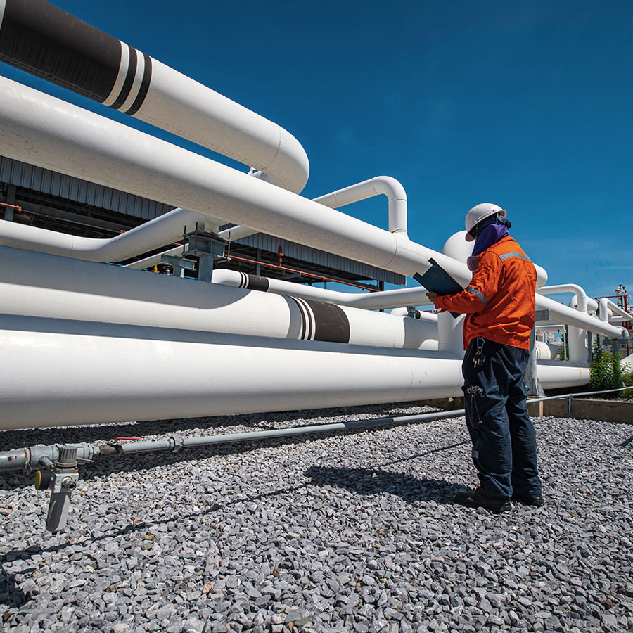 Industrie-Mobil Techniker kontrolliert Rohrleitungen in industrieller Anlage bei Tageslicht